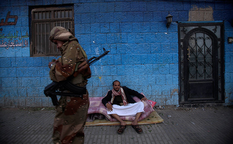 24 hours in pictures: A Yemeni soldier walks past an anti-government protestot