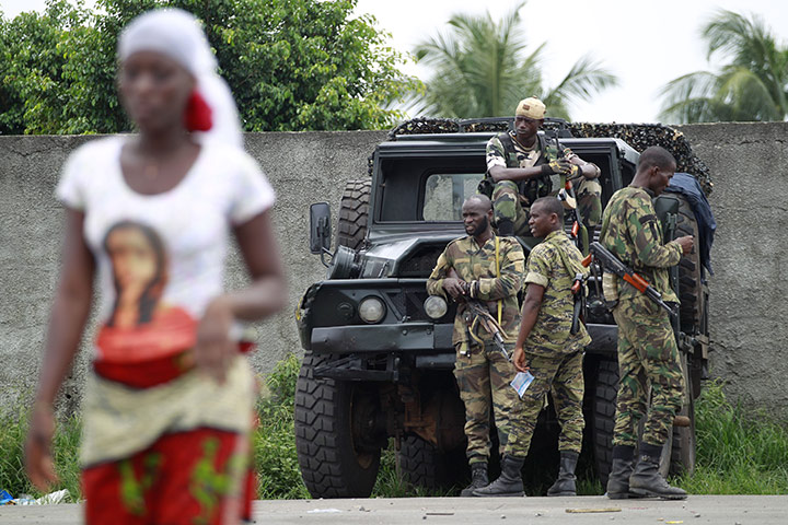 Ivory Coast: 5 April: A woman walks past soldiers loyal to Ouattara at a checkpoint
