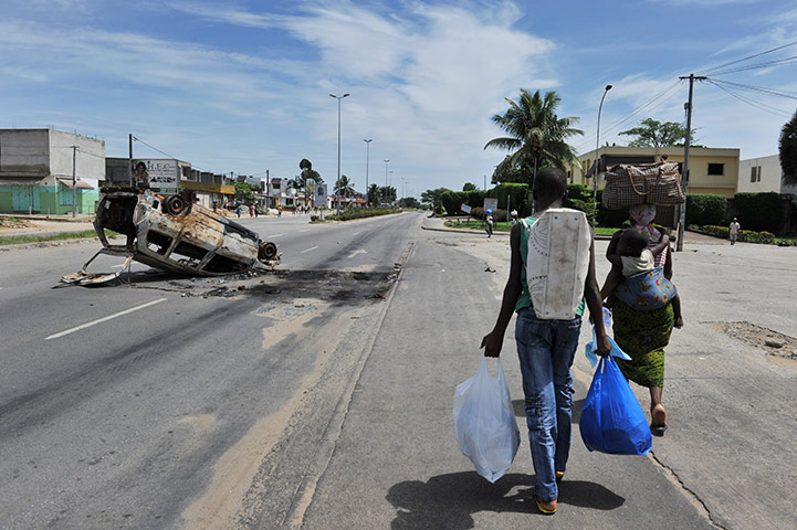 Ivory Coast: 5 April: Residents walk past a burnt car towards the Abobo district 