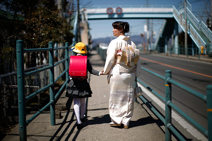 24 hours in pictures: A girl walks with her mother after her first day of school, Fukushima
