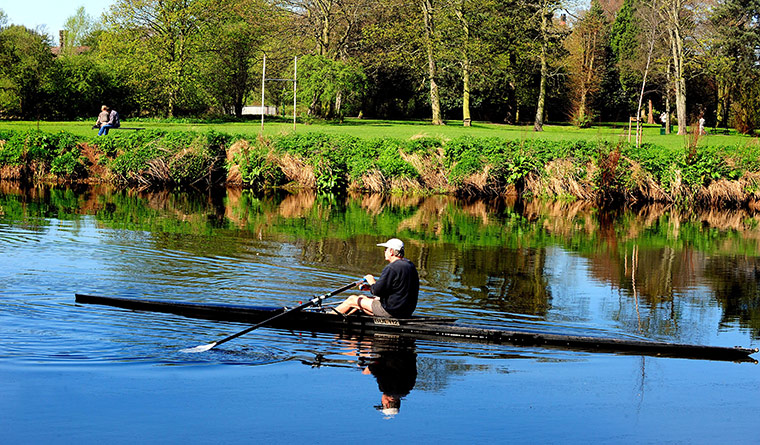 April Hot Weather: A man rowing in the river Trent at Washlands, Staffordshire