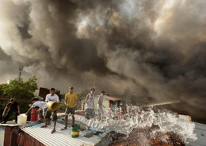 24 Hours in Pictures: Filipinos try to control a blaze as smoke rises from burning shanties