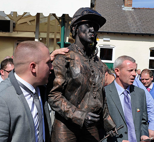 Grand National: A woman posing as a statue of a jockey enjoys a joke with some punters