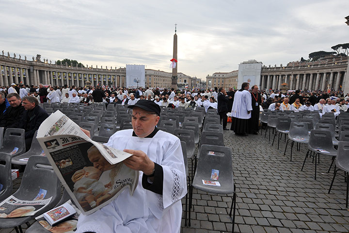 Beatification: A priest reads a newspaper as he waits for the ceremony 