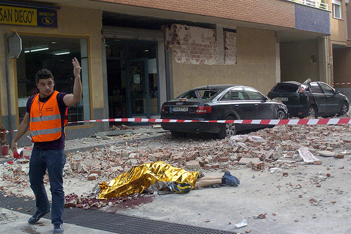 Lorca earthquake: A man gestures next to a body covered with a blanket in Lorca