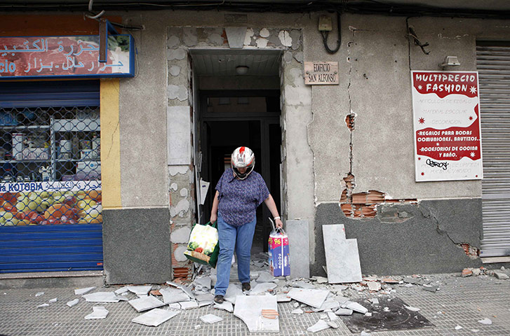 Lorca earthquake: A resident wearing a helmet carries bags from a building 