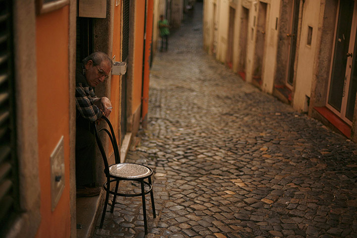 24 hours in pictures: A man rests on a chair at the entrance of his bar in in Lisbon