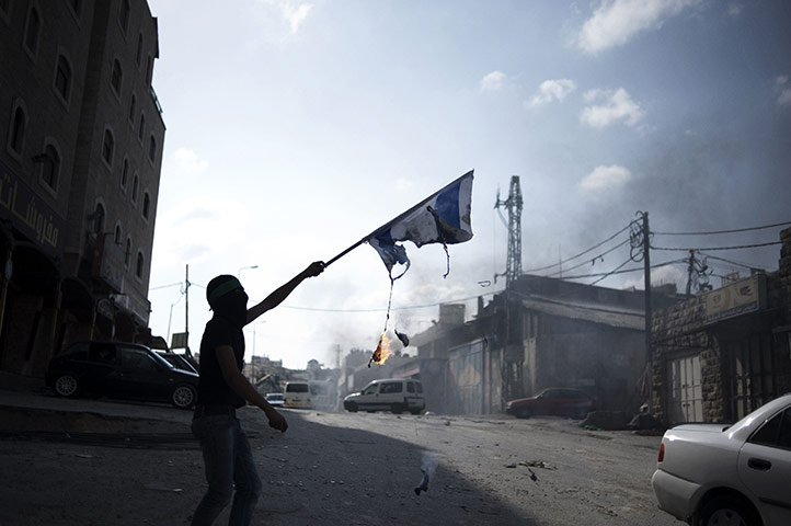 24 Hours: Palestinian demonstrators burn an Israeli flag during clashes with police
