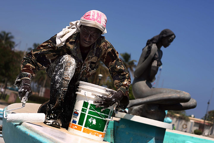 24 Hours: A Haitian worker paints a fountain for the presidential inauguration