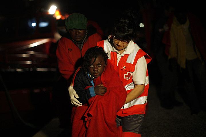 24 hours: Motril, Spain: A member of the Red Cross holds a child