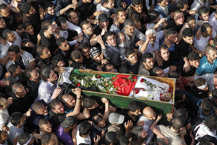 24 hours in pictures: Palestinians carry the coffin during a funeral in al-Yarmouk