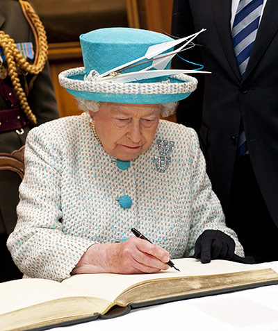 Queen in Ireland: The Queen signs a visitors book at the Government Buildings in Dublin