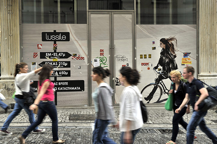 Business Week: People walk by closed store in central Athens