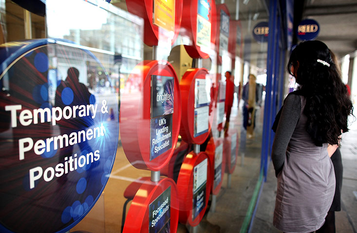 Business Week: A woman checks employment vacancies in window