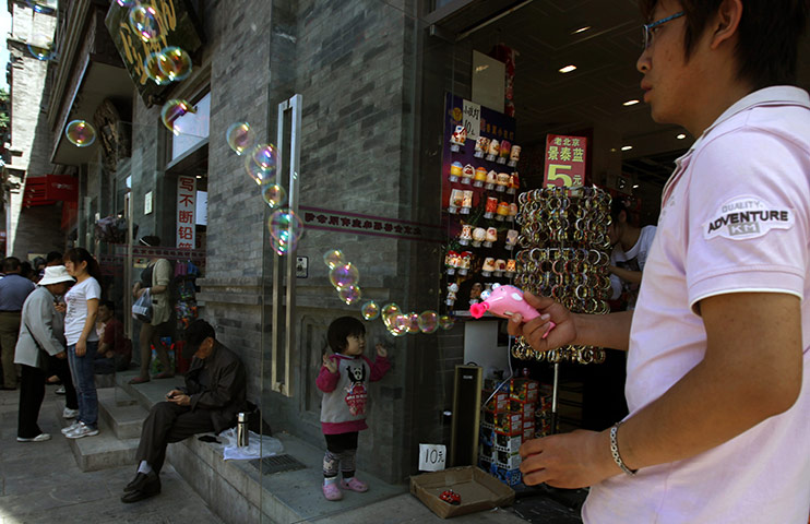 24 hours: Beijing, China: A child stands as a man uses a toy to make bubbles