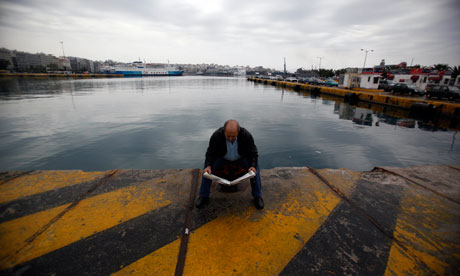 A man reads a newspaper at the port of Piraeus, during a 24-hours port strike in Greece 