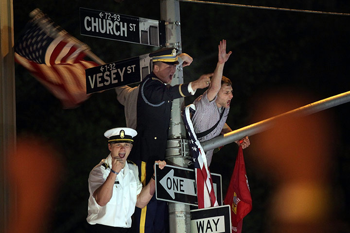 Bin Laden US reaction: Servicemen hang off a lamp post cheering in celebration at Ground Zero