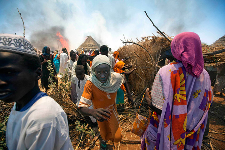 24 hours in pictures: Women and children run away with their belongings from a fire, North Dafur