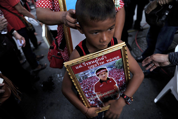 24 hours in pictures: A Thai boy carries a framed picture of a relative who died