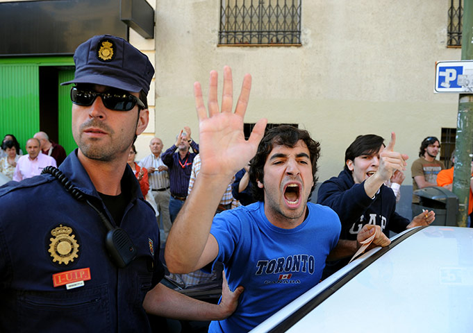 elections in spain: A policeman holds back protesters as Zapatero votes