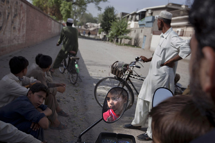 24 hours: Peshawar, Pakistan: A boy is reflected in a side mirror of a motorcycle