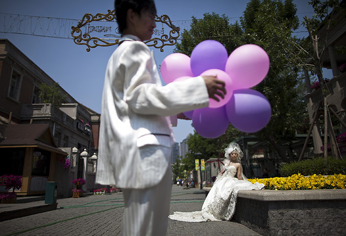 24 hours: Tianjin, China: A groom holds balloons as his bride poses for photographs
