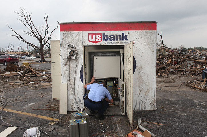 Tornadoes in US: An armoured car courier works on salvaging cash from an ATM 