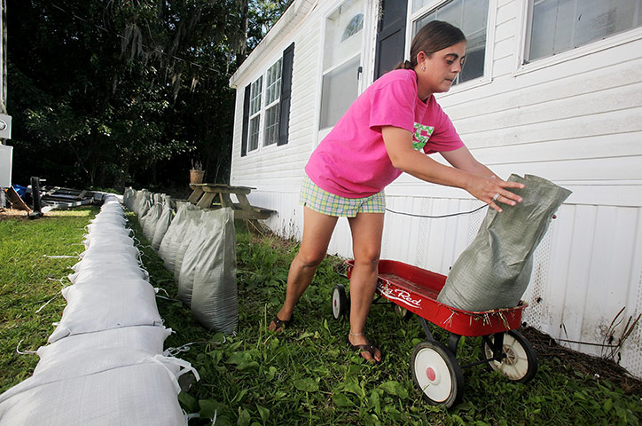 FTA Mario Tama: A woman moves sandbags with a toy wagon as she constructs a sandbag berm