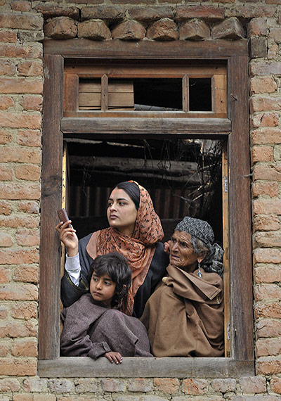 24 hours in pictures: A Kashmiri Muslim family watches a funeral from a window