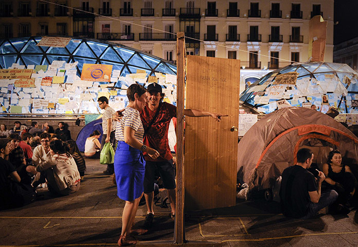 24 hours in pictures: Man invites a woman to go through a door at Puerta del Sol square