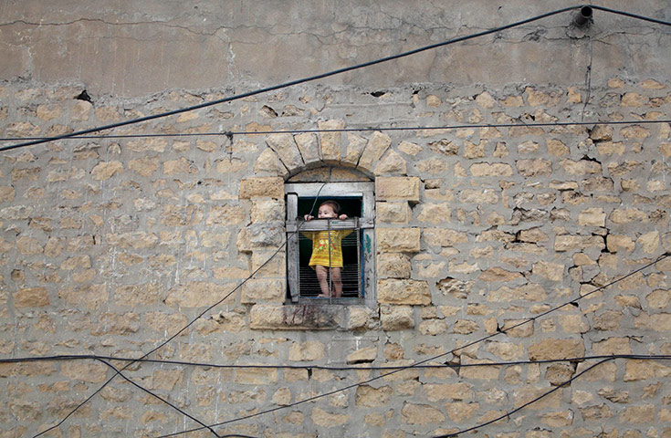 24 hours in pictures: A boy looks at power lines outside a window of a buiding in Karachi