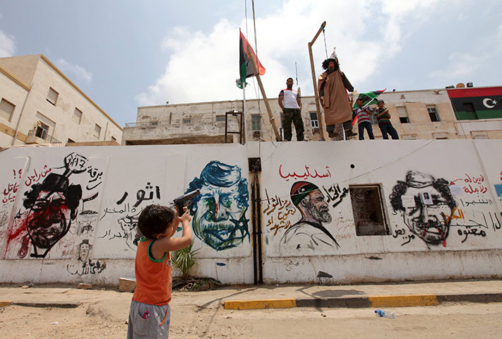 Middle East Unrest: A boy points a toy gun to the effigy of Muammar Gaddafi in Benghazi
