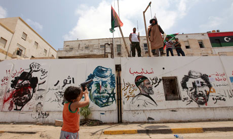 A Libyan boy points a toy gun to the effigy of Libyan leader Muammar Gaddafi