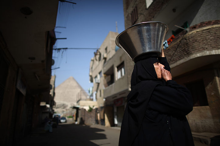 24 hours: Giza, Egypt: A woman carries a food bowl on her head in El Saman