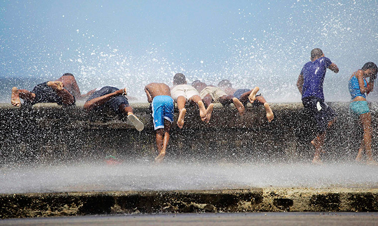 24 hours in pictures: Youths lie on Havana's seafront boulevard as waves crash