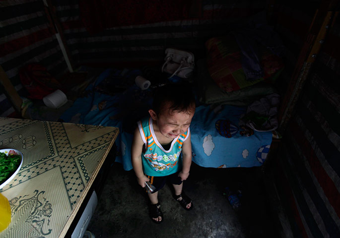 24 hours in pictures: A child from a migrant worker family cries next to a bed, China