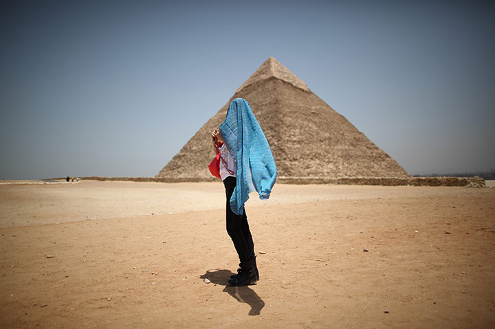 24 hours in pictures: A tourist covers her head against the sun in sight of a Pyramid