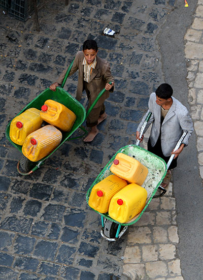 Yemen: Yemeni boys transport cans filled from a water point in Sana'a