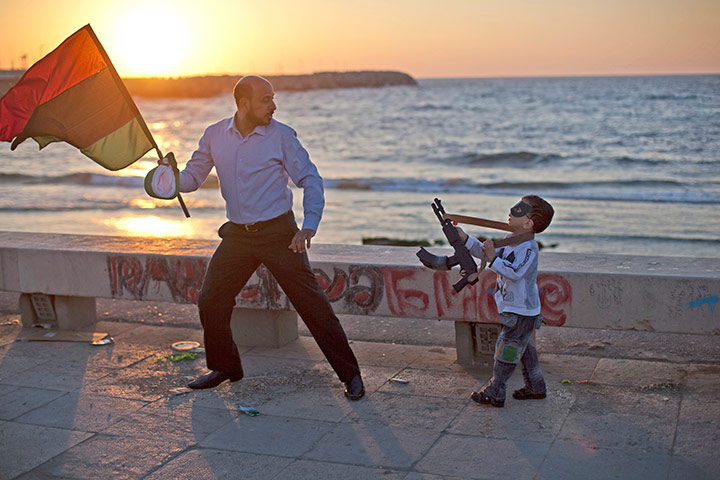 24 hours in pictures: A man plays with his son along the seafront in Benghazi, Libya