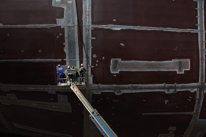 24 hours in pictures: Dalian, China: Workers examine the hull of a ship at the Dalian shipyard