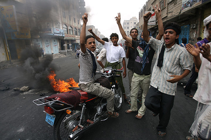 Yemen fighting: Yemeni youths shout slogans as they block a road in Taiz