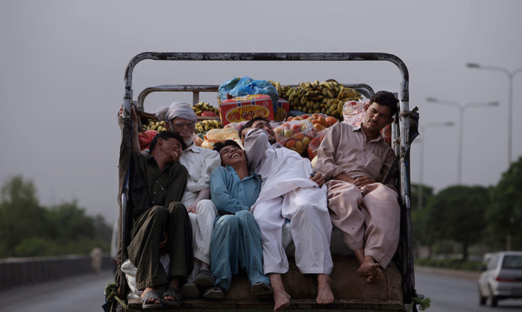 24 hours in pics: Pakistani men sitting on the back of a vehicle