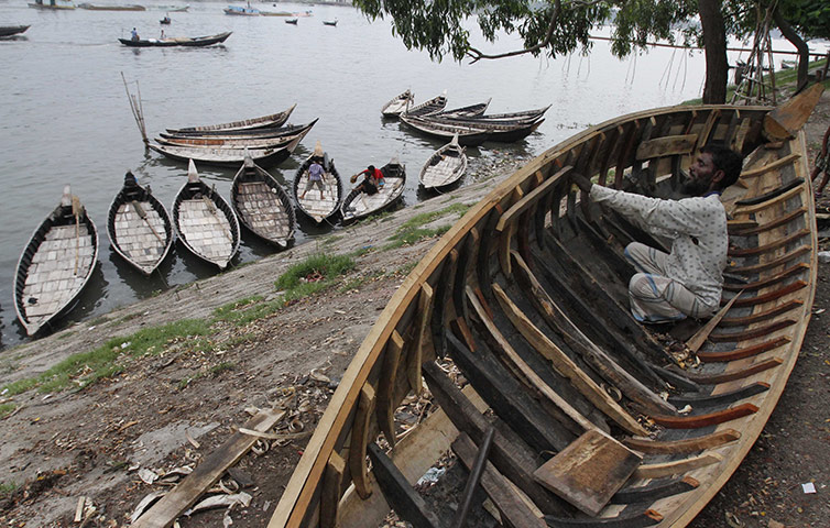 24 hours: Dhaka, Bangladesh: A boatman mends his boat before the monsoon rains