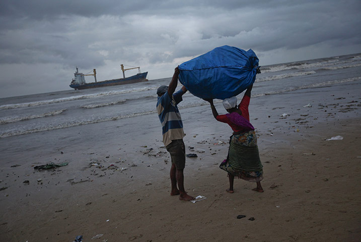 24 hours: Mumbai, India: A beach goer helps a woman lift a bag of recyclables