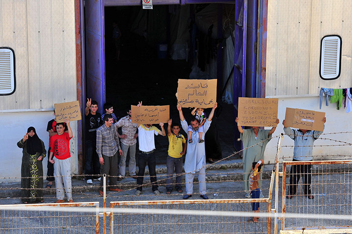 Syrian refugees: Syrian refugees hold up placards at the Turkish Red Crescent camp