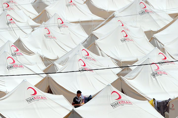 Syrian refugees: A Syrian refugee walks past tents at the Boynuyogun Red Crescent camp 