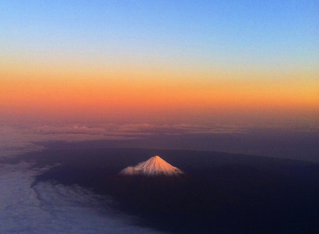 24 hours: New Zealand: Mount Taranaki has a warm glow lighting the snow peak 