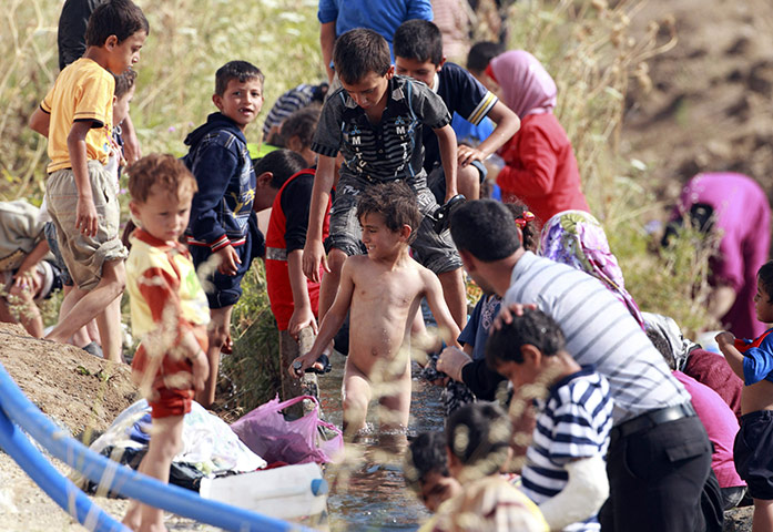 syrian refugees: A boy takes a bath in an irrigation canal