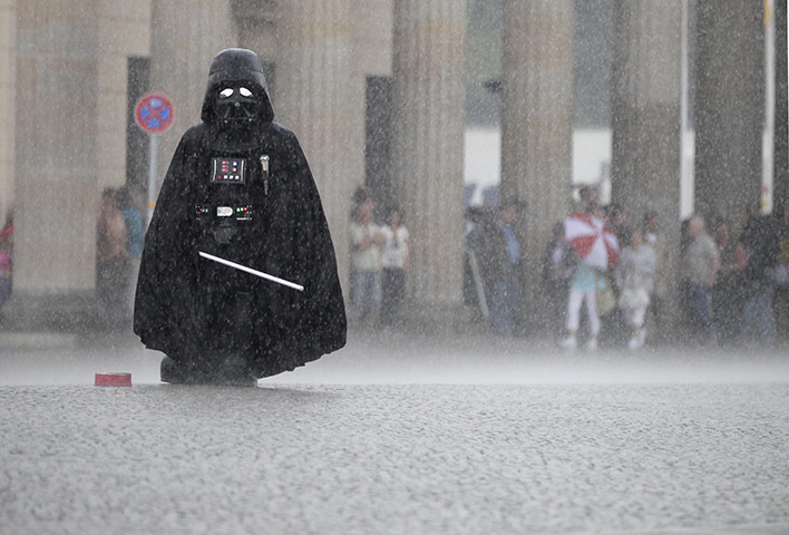 24 hours in pictures: Berlin, Germany: An actor in a Darth Vader costume waits for tourists 