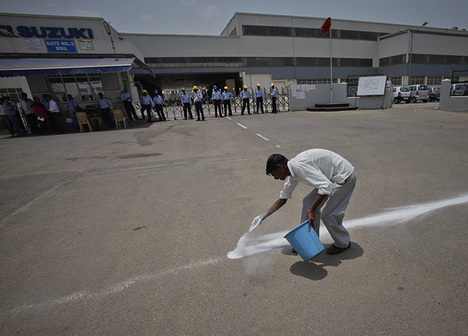 24 hours in pictures: Manesar, India: An employee draws a line with chalk powder